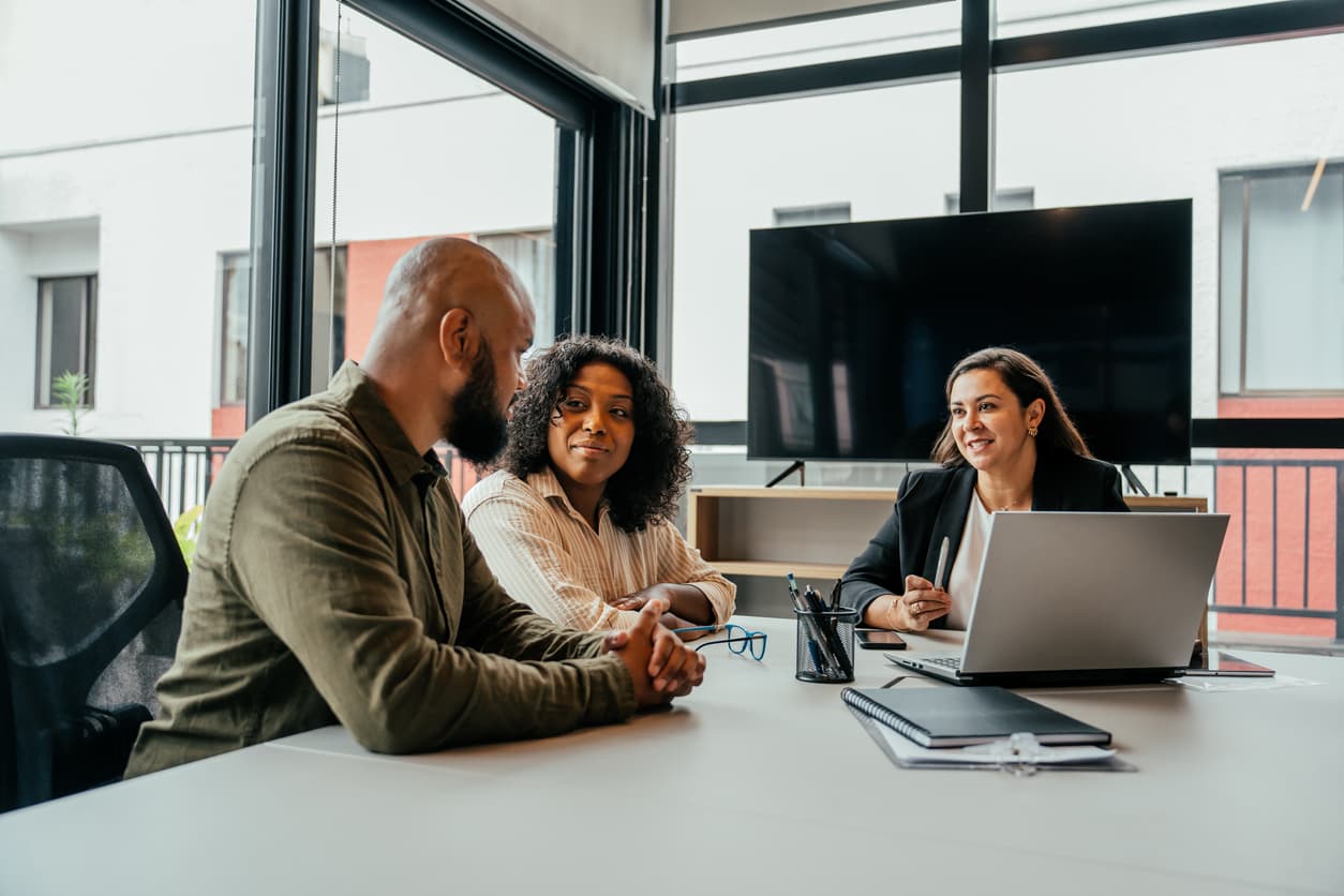 Financial advisor meeting with a couple across a desk in a bright office